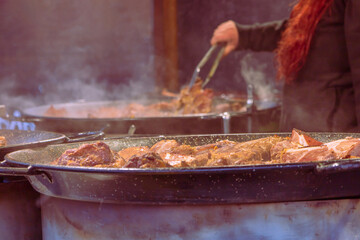 Food in a large round pan and grill placed on the counter and intended for sale in the market to customers.