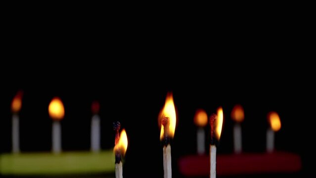 Three Burning Matches with a Bright Flame on a Black Background in Empty Space. Dark room. Texture. A row of matches, burning sulfur heads, charred matches. Blurred motion. Macro. Slow motion.