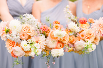 Bridesmaids wearing soft blue dresses holding small flower bouquets in soft colors to compliment their outfits.