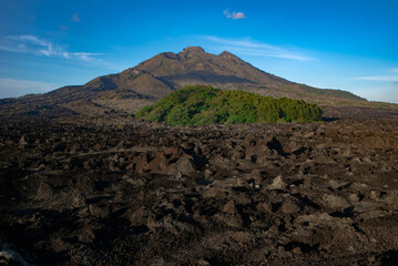 Landscape view of solidified black volcanic lava flows around the slopes of an active volcano Batur, Bali island.