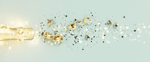 Flat lay of Celebration. Champagne bottle and golden decoration on blue background