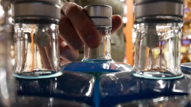 Close-up of blue gin bottles on a liquor store shelf and buyer chooses one