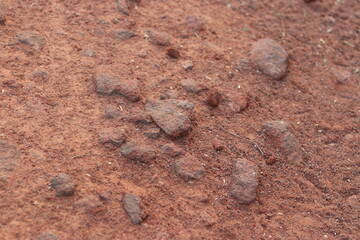 Red and brown pebbles and dirt on the ground in sunlight, large pebbles