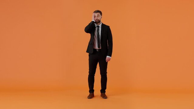 Young businessman in formal outfit is looking disappointed and showing facepalm gesture