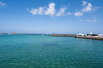View of the Fermina islet. Turquoise blue water. Sky with big white clouds. Seascape. Lanzarote, Canary Islands, Spain.