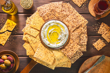 Collection of delicious healthy crackers with fresh herbs on top. Served with creamy dip, pickled...