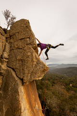 Person climbing in high mountains with yellow jacket rope and helmet in nature, confidence and risk, safety