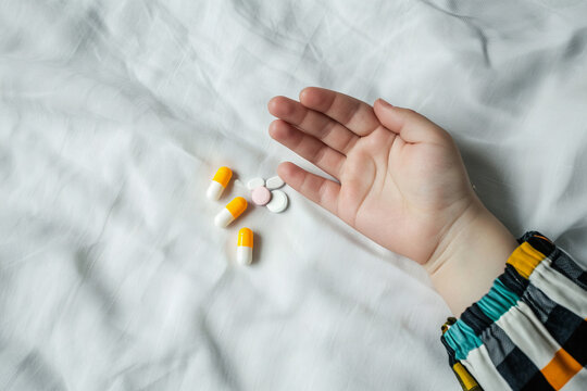 A child's hand is holding a handful of pills and capsules, Generative Ai