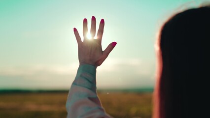 Hand of young girl reaches out to sun. Young woman extends her hand towards dawn. Sunlight between fingers of girls hand. Happy teenager dream, stretches out his hand to sun. Prayer to God sky peace
