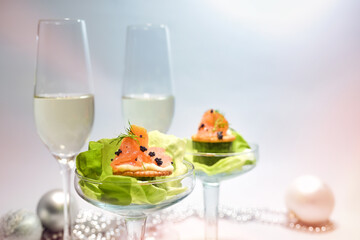Smoked salmon appetizer with caviar and lettuce in glasses, two champagne flutes and holiday...