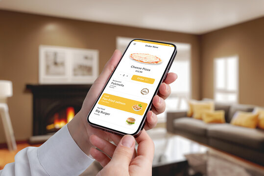 Smartphone with a fast food app in hand, woman enjoying pizza and burger options in a cozy living room background. Order now for a delicious feast