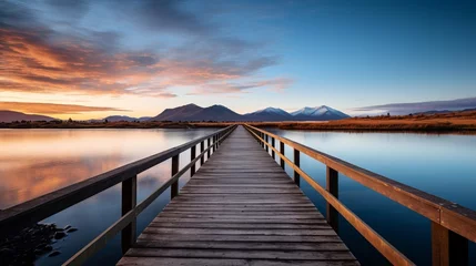 Fototapeten A vertical video showing a wooden passage over a small lake that is reflective and a mountain range on the horizon © Tahir