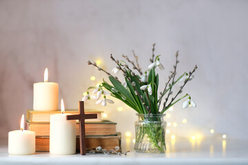 Bouquet of Snowdrop flowers with willow branches, christian cross, religion books and candles on...