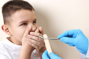 The boy covers his mouth with his hands to protect himself from the examination of the teeth of the oral cavity. Healthcare and dental care concept.