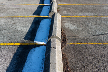 long triangular forms at the edge of parking spaces known variously as wheel stops, parking blocks, or parking curbs  - obrazy, fototapety, plakaty