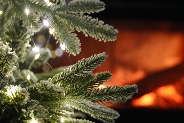 White green leaves close up of the christmas tree with the chimney and lights in the background.