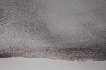 Black glitter Ink watercolor grain blot on gray paper texture background.