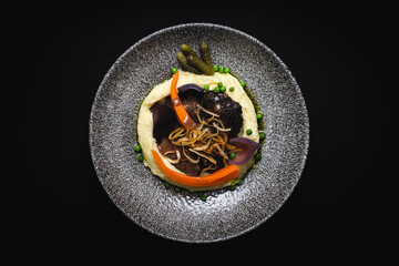 Restaurant food serving, mashed potatoes with baked grilled vegetables on a black background.