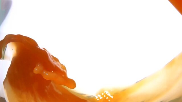 An appetizing wave of orange juice swirls inside the glass