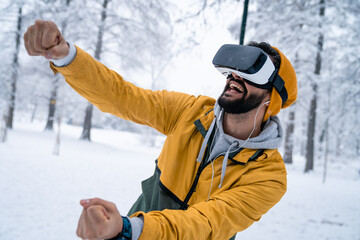 Handsome man playing video games in VR goggles wearing virtual reality headset on his head while...