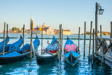 Fotobehang Waiting gondola covered up for night at canal pier with church and spire in background. © Brian Scantlebury