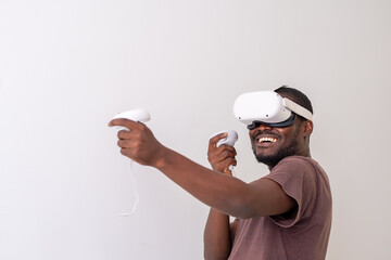 Excited Black Man wearing VR headset playing virtual reality game holding controllers. Man playing...