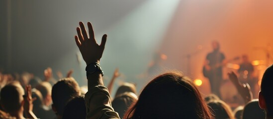 Blurry photo of Christians worshiping God together in a church hall, raising hands in praise, with a music concert backdrop. - obrazy, fototapety, plakaty
