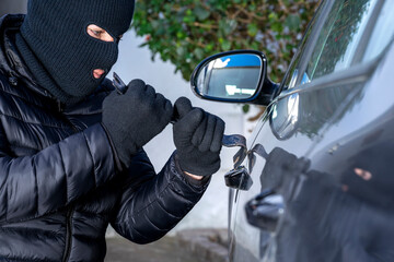 MASKED THIEF IN BALACLAVA WITH CROWBAR STEALING A CAR. INSURANCE AND ANTI THEFT SYSTEM.