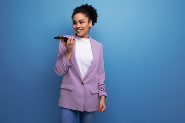 young smiling hispanic business woman with curly hair dressed in a stylish office jacket is dialing...