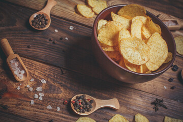 Lots of crispy chips and spices on a wooden surface, fast food and snacks