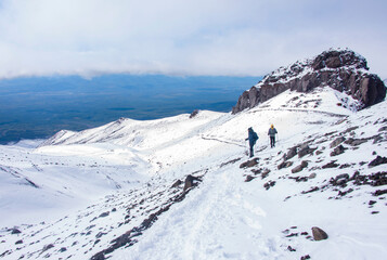 There are two alpinists on the foreground. They are walking up on Avacha volcano. There is a green...
