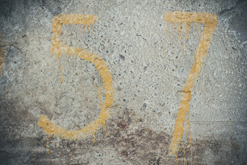 Yellow numbers on a concrete wall, number 57