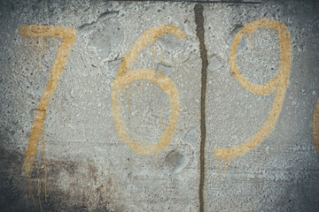 Yellow numbers on a concrete wall, number 7, 6, 9