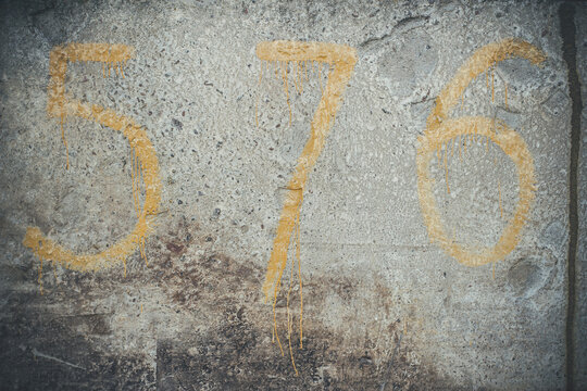 Yellow numbers on a concrete wall, number 5, 7, 6