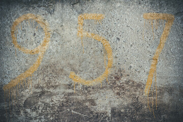 Yellow numbers on a concrete wall, number 9, 5, 7