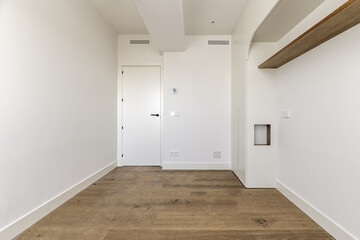 An empty bedroom with some custom furniture built into the wall and wooden floors