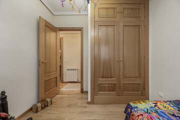 A bedroom with a built-in oak wardrobe, matching floors and access to the hallway