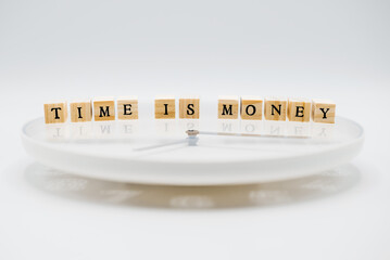 A clock with &lsquo;Time is money&rsquo; written on it in wooden letter cubes