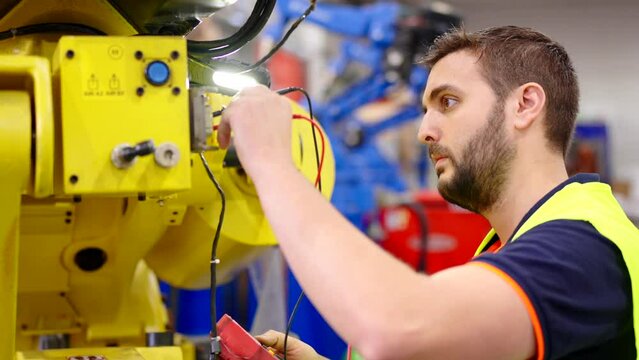 Professional electrician using tester in a factory. Maintenance engineer working in industrial robot