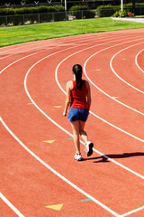Young Hispanic Teen Girl Walking On Track In Blue Shorts Red Top