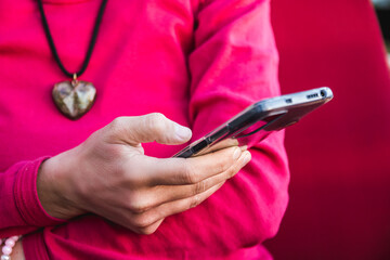 A woman in a red sweater is texting on a mobile phone