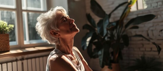 Elderly woman practicing mindful breathing in fitness attire for relaxation and peace at home.