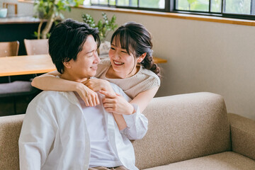 家のリビングにいる仲良しの若い日本人夫婦（スキンシップ）
