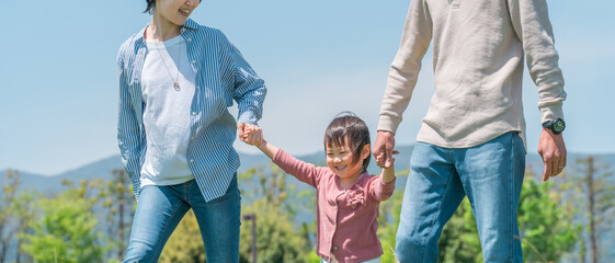空の見える公園で手を繋いでジャンプして遊ぶ子供と両親のアジア人家族・ファミリーイメージ
 - obrazy, fototapety, plakaty