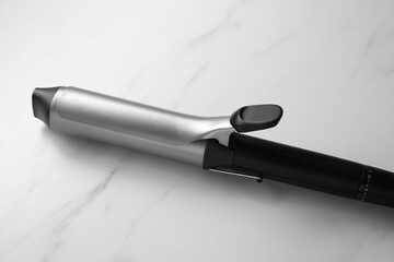 Hair curling iron on white marble background