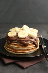 Tasty pancakes with chocolate spread and sliced banana served on gray table