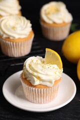 Delicious lemon cupcakes with white cream on black table, closeup