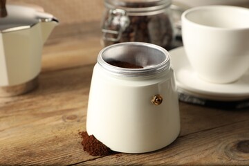 Moka pot and ground coffee on wooden table, closeup