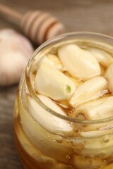 Fototapeta na wymiar Honey with garlic in glass jar on table, closeup