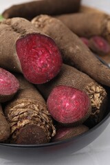 Whole and cut red beets in bowl on table, closeup